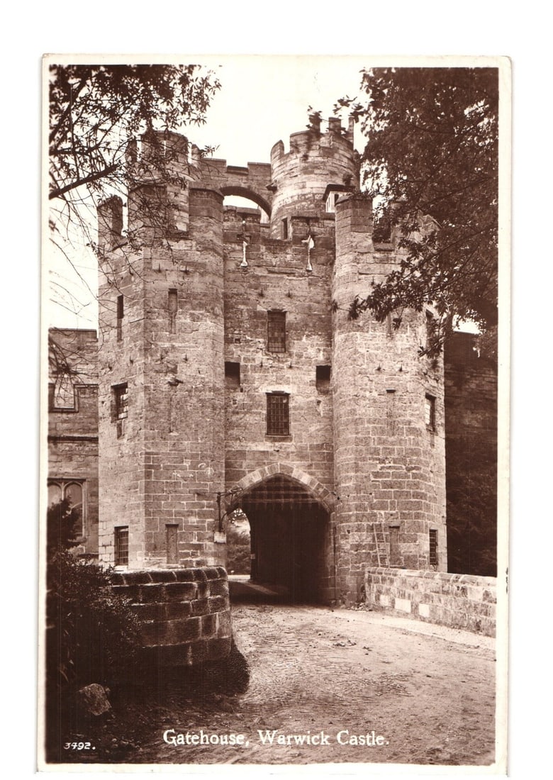 Historic Gatehouse of Warwick Castle, England, Early 20th Century Real Photo Postcard View: A sepia-toned real photograph depicts the Gatehouse of Warwick Castle, a large stone structure featuring multiple towers, battlements, and an arched entranceway. The gatehouse is constructed of rough-