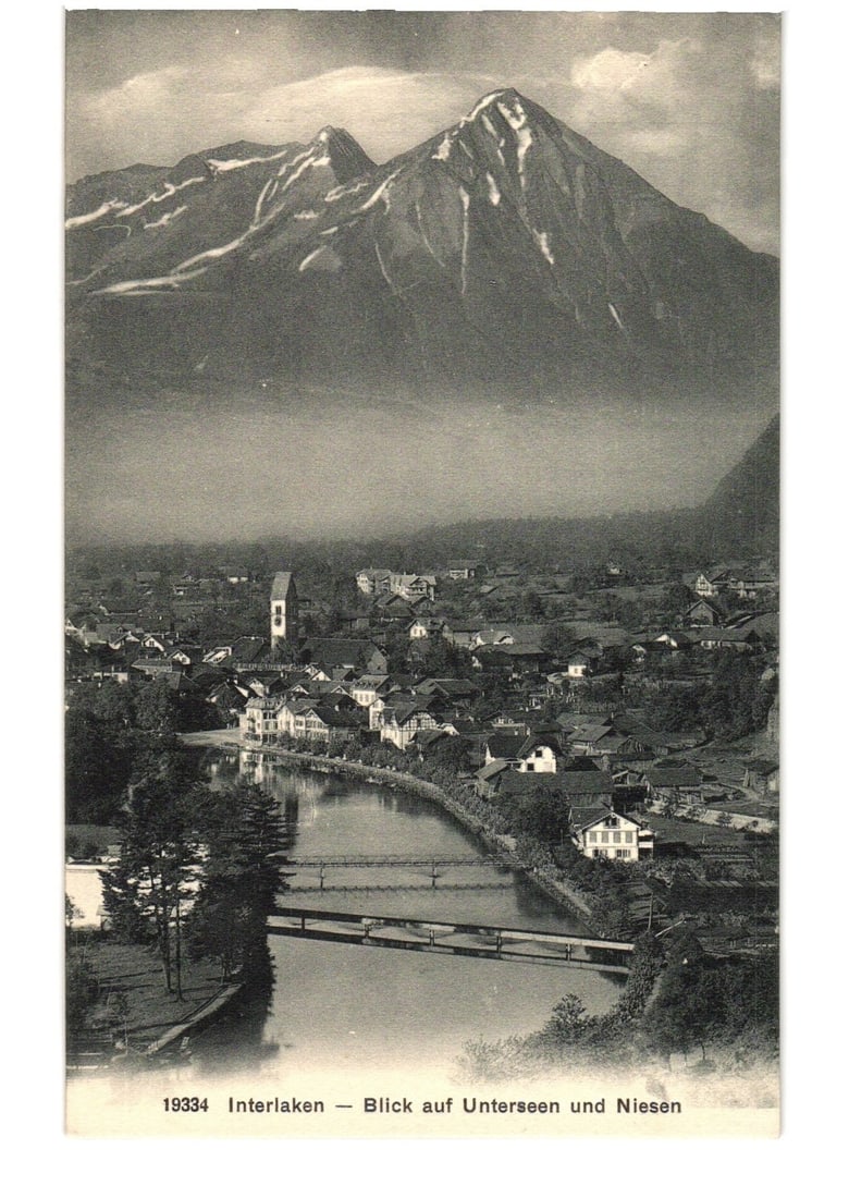 Interlaken, Switzerland Panoramic View of Unterseen and Niesen Mountains Photographic postcard: A panoramic photographic postcard view depicts the town of Interlaken in Switzerland, nestled in a valley with a river winding through its center. The foreground shows dense foliage and the river, spa