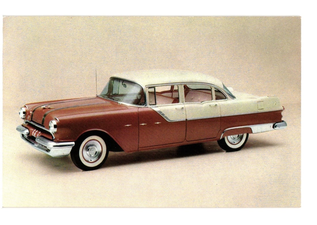Vintage 1950s Pontiac Star Chief Custom Four-Door Sedan promotional postcard, White Mist over: A vintage Pontiac Star Chief Custom Four-Door Sedan is depicted in a two-tone paint scheme of White Mist over Firegold. The automobile is shown from a three-quarter front perspective, angled slightly 