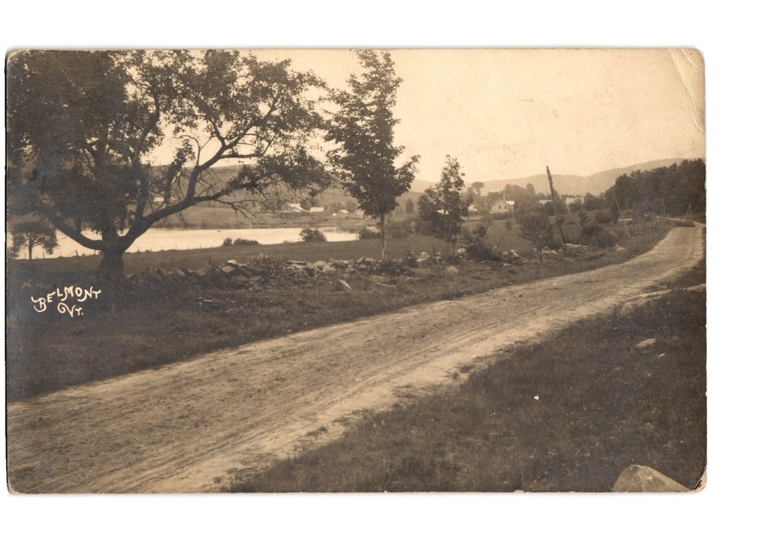 Early 20th Century Real Photo postcard of a rural road, lake, and village in Belmont, Vermont: A sepia-toned Real Photo Postcard (RPPC) features a rural dirt road winding through a landscape in Belmont, Vermont. Large deciduous trees stand on the left foreground, with a body of water visible be