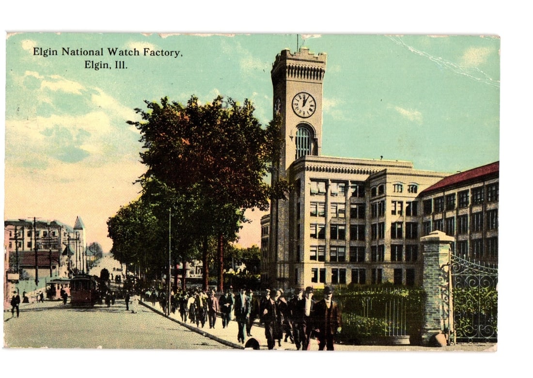 Elgin National Watch Factory and Street Scene Postcard, Elgin, Illinois, ca. 1912: The Elgin National Watch Factory building, featuring a prominent clock tower with a visible clock face, dominates the right side of the image. The multi-story factory is constructed of light-colored m