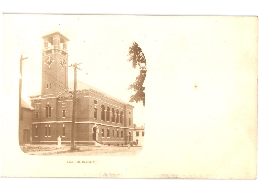 Early 20th Century photographic postcard of Brookfield Town Hall featuring a clock tower.: A sepia-toned photographic image depicts a brick institutional building, identified as the Town Hall in Brookfield. The building features a prominent clock tower on its left side, with arched windows 