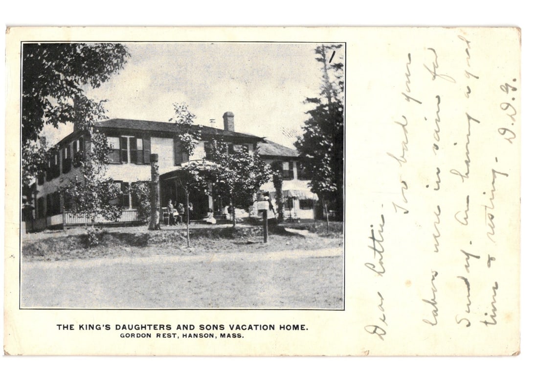 The King's Daughters and Sons Vacation Home, Gordon Rest, Hanson, Mass., 1906 postcard.: A large, multi-story wooden house with a wide porch stands centrally framed, surrounded by trees. A road extends across the foreground. The house features multiple windows, dark shutters, and a promin