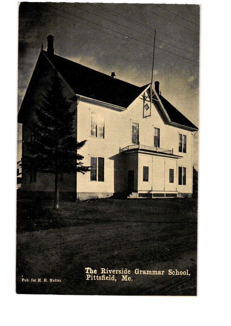 Historic Riverside Grammar School, Pittsfield, Maine, early 20th-century architectural postcard.: A two-story white clapboard building, identified as The Riverside Grammar School, Pittsfield, Maine, is depicted from a slightly angled perspective. The structure features a prominent peaked roof, mul