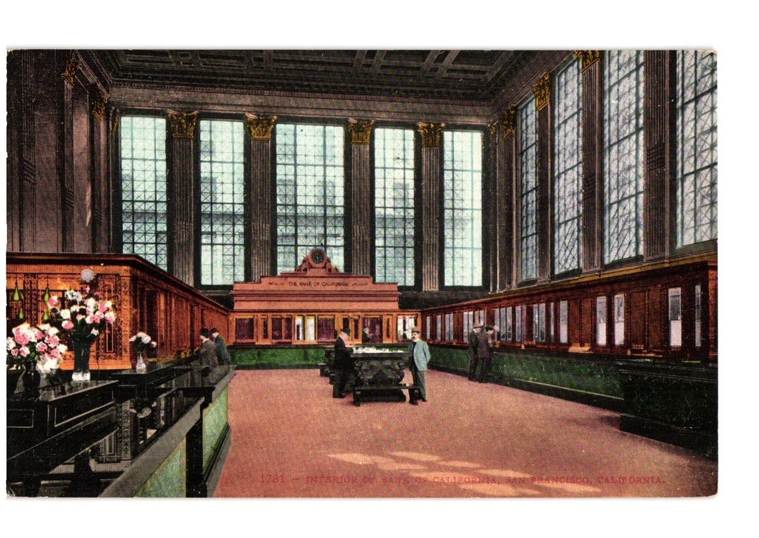 Interior of The Bank of California, San Francisco, circa 1900s-1910s, collectible postcard.: A grand banking hall, featuring high ceilings supported by classical columns and large, multi-paned windows. Dark wood paneling and green-accented counters line the space. Several individuals in perio