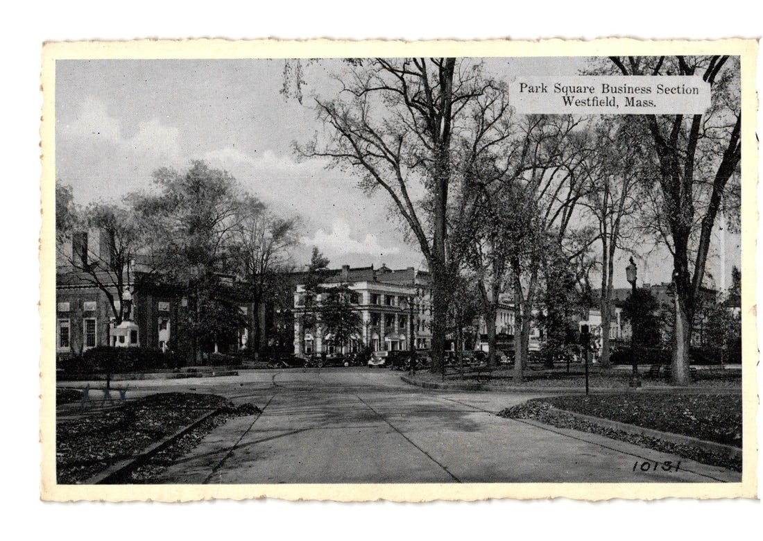 Park Square Business Section Street View, Westfield, Mass., early 20th Century photographic postcard: A photographic view of the Park Square Business Section in Westfield, Massachusetts. The image features a wide street or plaza curving through the foreground, flanked by mature trees. Several multi-st