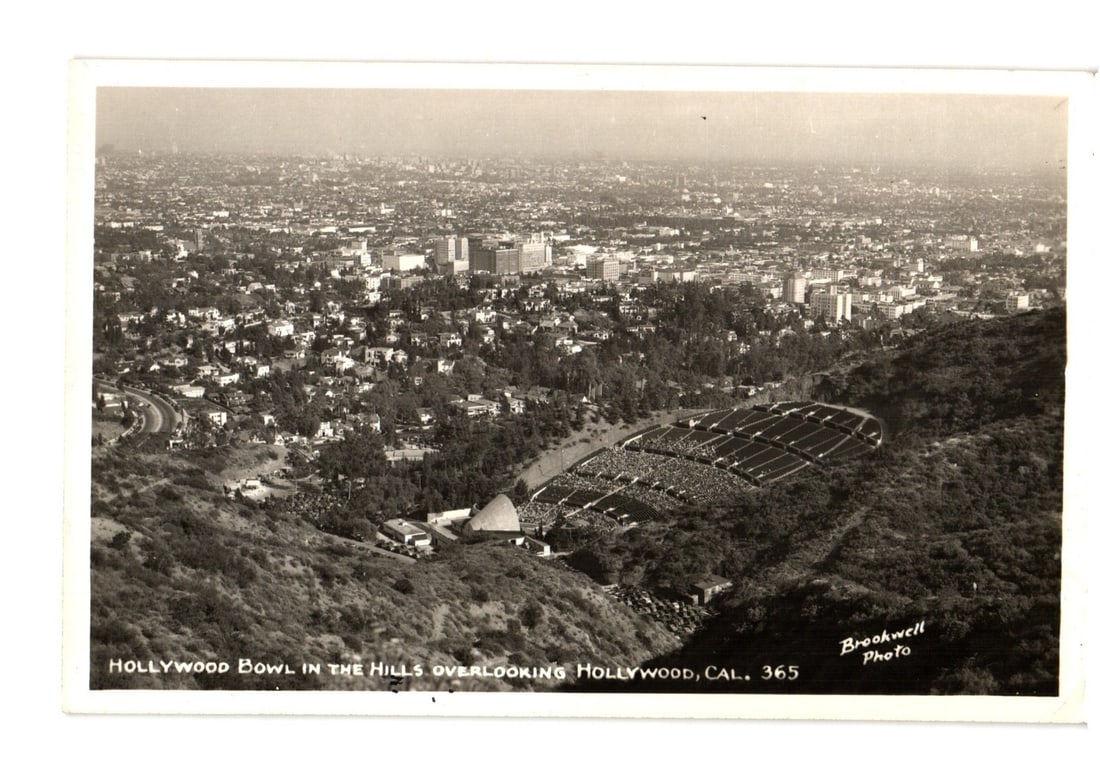 Panoramic Aerial View of Hollywood Bowl and Sprawling Hollywood, California Real Photo Postcard: A panoramic aerial black and white photographic image captures the Hollywood Bowl nestled in hills, overlooking a vast urban landscape of Hollywood, California. The amphitheater, with its distinct she
