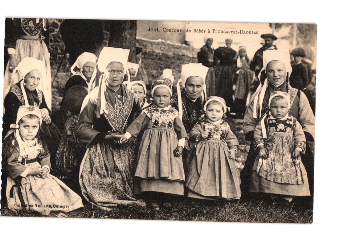 Breton Baby Contest, Plougastel-Daoulas, France, with Women & Children in Traditional Dress postcard: A group portrait of ten individuals, primarily women and young children, arranged in rows. The subjects wear traditional Breton costumes, characterized by elaborate white coifs and patterned garments.