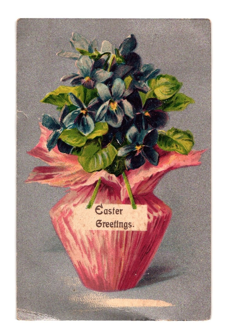 Easter Greetings Violets Floral Bouquet Chromolithograph Postcard, Long Island City, 1909: A vibrant chromolithograph depicts a bouquet of dark purple and blue violets with green leaves, presented in a pink vase or pot. The vase is wrapped in a lighter pink fabric. A small white tag hangs f