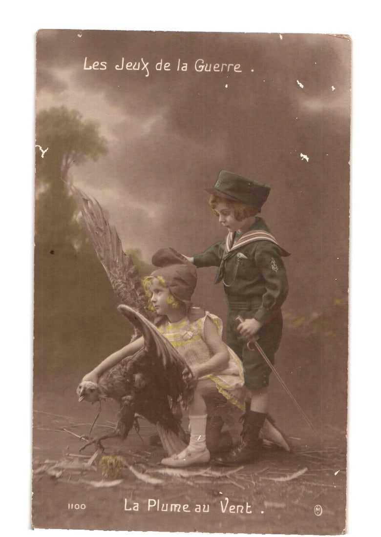 Sepia Toned Postcard Depicting Children in 'The Games of War' with a Large Bird: An older boy dressed in a dark green military-style sailor uniform, complete with a hat and a short sword, stands behind a younger girl. The girl, wearing a light-colored dress and a dark cap, kneels 