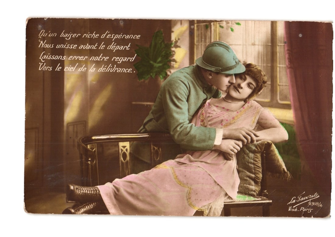 Vintage WWI Era Postcard: French Soldier in Uniform Embraces a Woman Romantically: A romantic scene depicts a soldier in a light blue-green uniform and helmet embracing a woman in a pink dress. The soldier is seated, leaning over the woman who reclines against him, their faces close