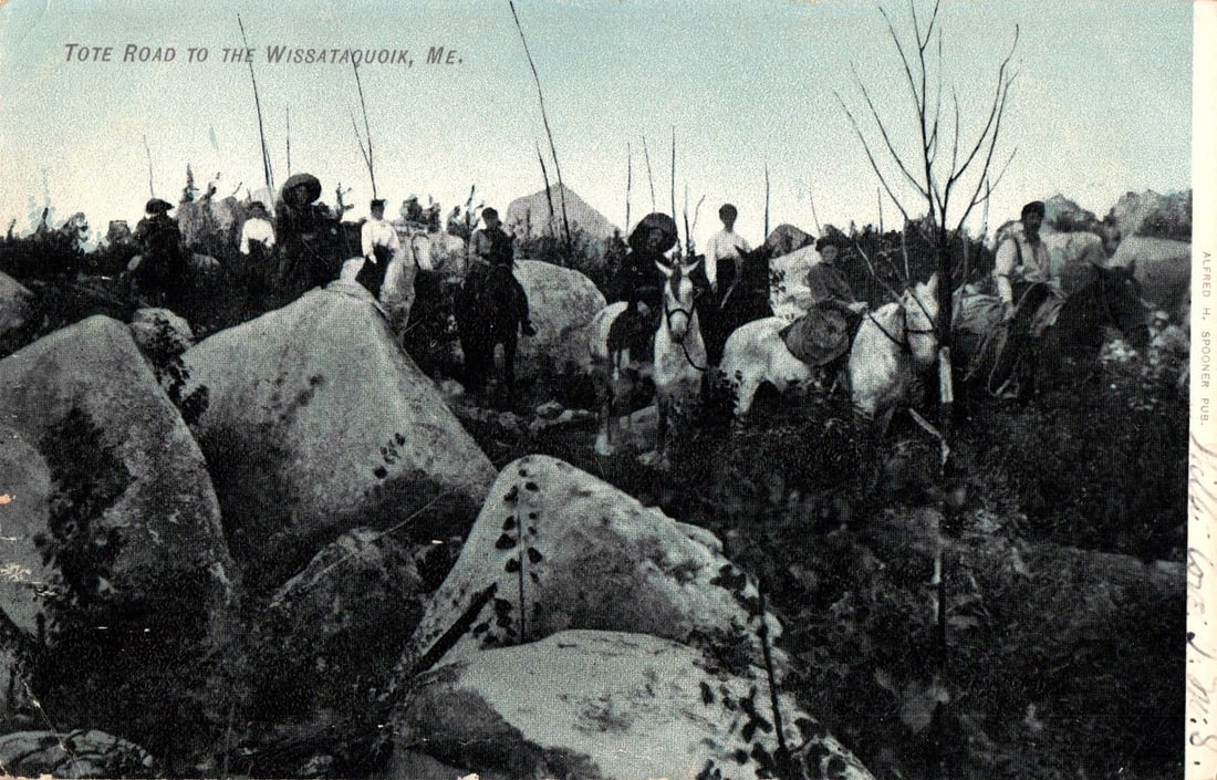 Group of Horseback Riders on a Tote Road to Wissataquoik, Maine, Early 1900s Postcard: A group of horseback riders traverses a rocky tote road, with large boulders and dense vegetation in the foreground and mid-ground. Several men are visible on horses, ascending what appears to be a ch