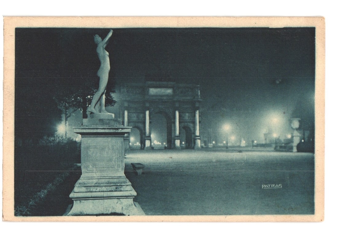 Early 20th Century Paris by Night Postcard: Tuileries Gardens Statue and Archway.: A monochrome photographic image, tinted greenish-blue, depicts a nocturnal scene in the Tuileries Gardens. In the left foreground stands a classical nude female statue on a stone pedestal, arms raised