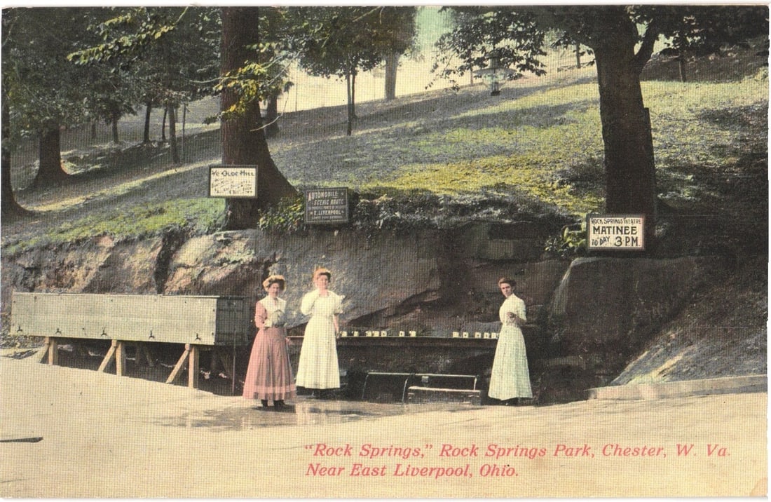Three Women at Rock Springs Park, Chester, W. Va. Bathing Matinee Postcard, Early 1900s.: Three women in long dresses are depicted at a natural spring or water feature within a park setting. Two women stand together on the left, and one woman stands to the right, all positioned near a long