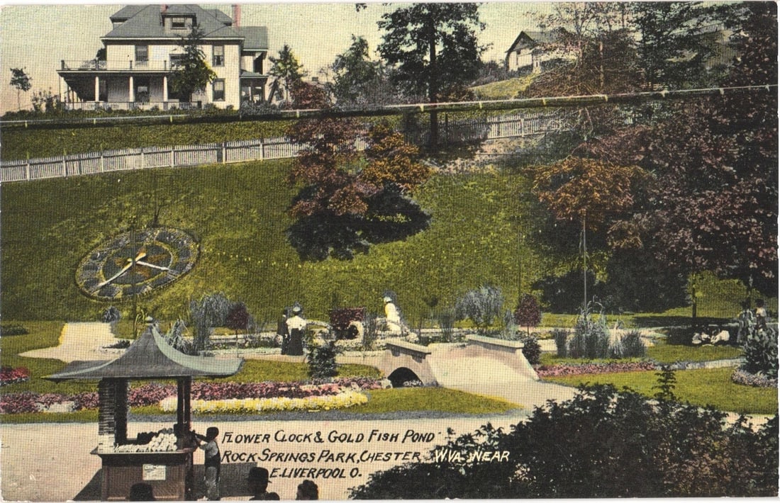 Flower Clock & Gold Fish Pond, Rock Springs Park, Chester, W.VA near East Liverpool, O. postcard: A scenic view of Rock Springs Park, featuring a large flower clock embedded in a grassy hillside. Below the clock, a goldfish pond is visible with a small arched bridge spanning it. A pavilion with an