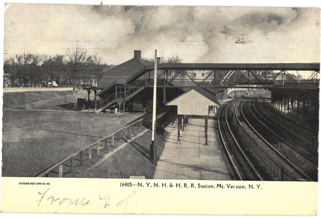 View of N. Y. N. H. & H. R. R. Station in Mt. Vernon, N.Y., an early 20th century postcard.: A panoramic view captures the N. Y. N. H. & H. R. R. Station in Mt. Vernon, N. Y., featuring the station building, platform, and multiple parallel railway tracks curving to the right. An elevated pede
