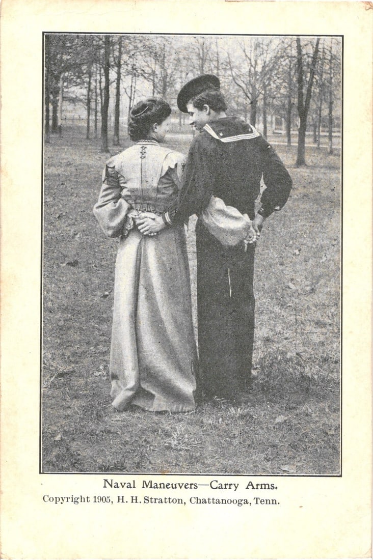 1905 Chattanooga postcard depicting 'Naval Maneuvers - Carry Arms' with a sailor and a woman.: A man in a dark U.S. Navy sailor's uniform and a woman in a light-colored, long-sleeved dress are depicted standing back-to-back, clasping hands behind their backs. They are positioned in a park-like 