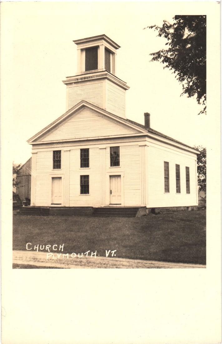 Plymouth, Vermont Church Building Real Photo Postcard with Steeple, Circa Early 20th Century: A sepia-toned Real Photo Postcard features a clapboard church building with a multi-tiered steeple. The structure presents a symmetrical facade with two entry doors and four windows. Steps lead to eac