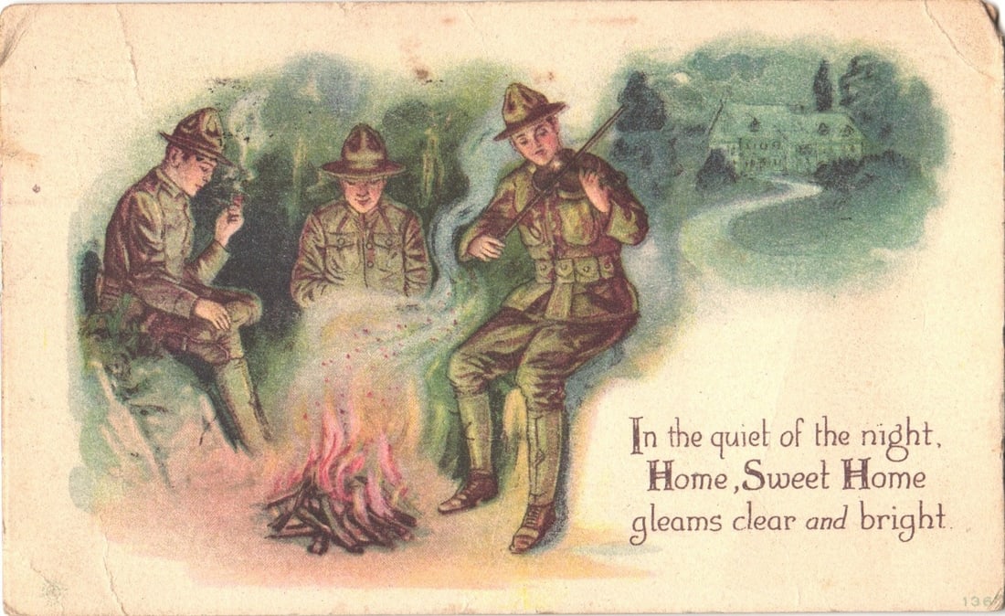 WWI Era Soldiers Around Campfire, One Playing Violin, with Distant Home at Night postcard: Three soldiers in olive drab uniforms and campaign hats are depicted gathered around a campfire at night. The soldier on the left is seated, holding a pipe. The central soldier is seated cross-legged,