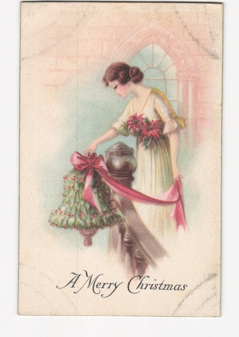 Artistic postcard depicting a woman decorating with a holly wreath and red ribbon for Christmas: Please review the photos carefully for additional condition details. Note that scans may appear slightly darker or lighter than the item's true appearance, and minor scanning artifacts may be visible.
