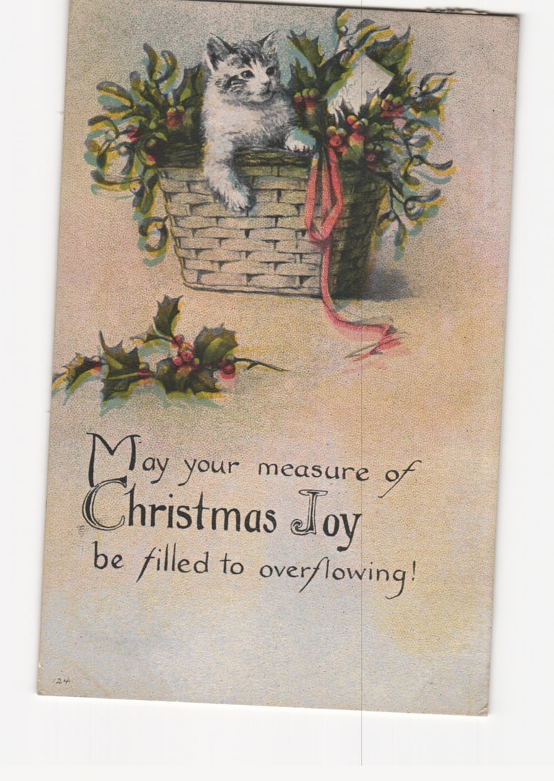 Early 20th Century Christmas postcard depicting a kitten in a holly-decorated basket with greeting.: Please review the photos carefully for additional condition details. Note that scans may appear slightly darker or lighter than the item's true appearance, and minor scanning artifacts may be visible.