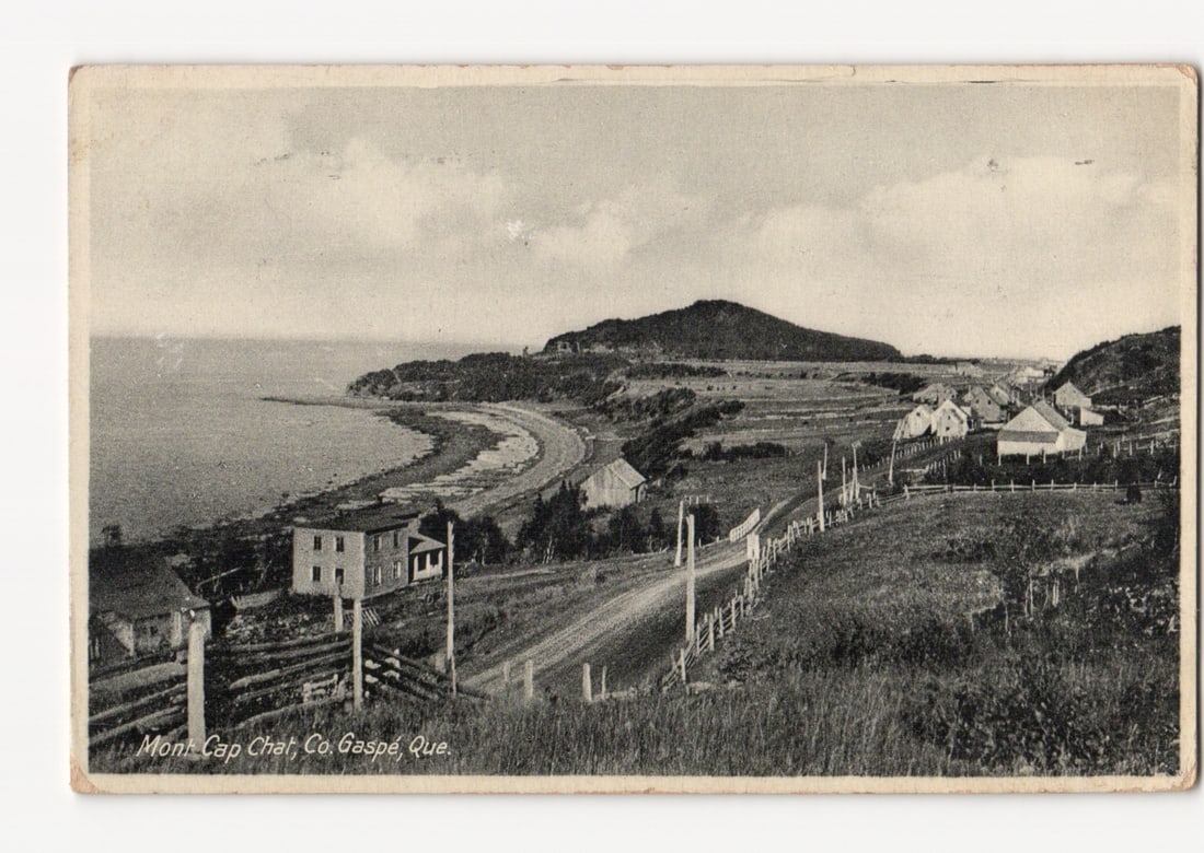 Black and White Coastal Landscape Postcard: Mont. Cap Chat, Gaspe, Quebec, Village and Bay: A monochrome photographic postcard depicts a coastal village in Mont. Cap Chat, County Gaspe, Quebec. The view presents a sweep of the bay with a curving coastline road and several houses nestled on t