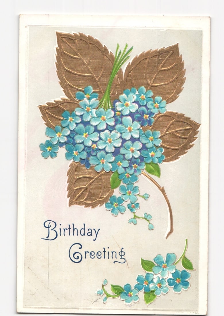 Vintage Embossed Chromolithograph Birthday Greeting Postcard with Blue Flowers, German-Made.: An embossed chromolithograph postcard features a central bouquet of numerous small, light blue flowers with yellow centers, set against several large, textured, gold-colored leaves. A slender brown st