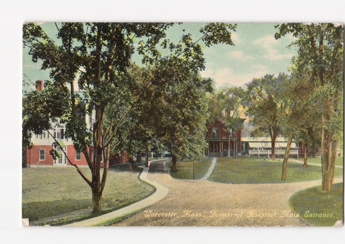Worcester, Massachusetts, Memorial Hospital Main Entrance Landscape Postcard, Circa 1910s: A landscape view depicting the Memorial Hospital in Worcester, Massachusetts, focusing on its main entrance. Large deciduous trees with full green foliage frame the scene and partially obscure the mul