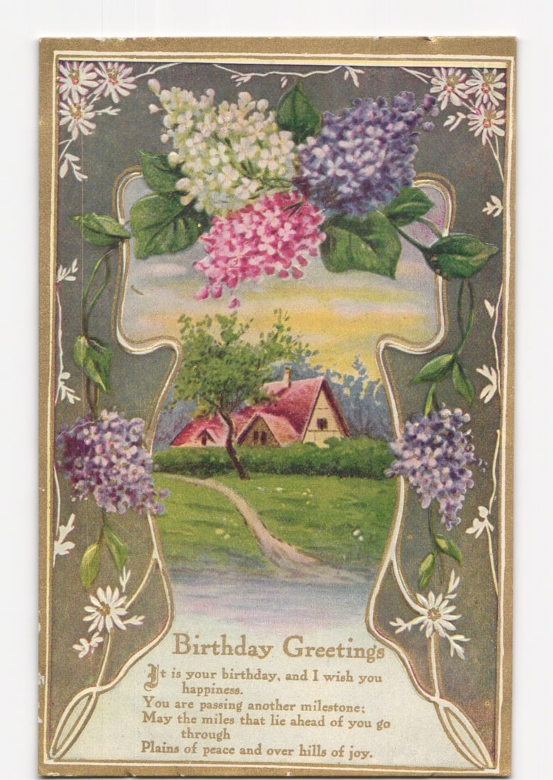 Early 20th Century Birthday Greetings postcard with Lilac Flowers and Rural Landscape: A chromolithograph postcard features a central vignette depicting a rural landscape under a colorful sky, with two red-roofed houses nestled among green trees and bushes. A dirt path leads from the fo