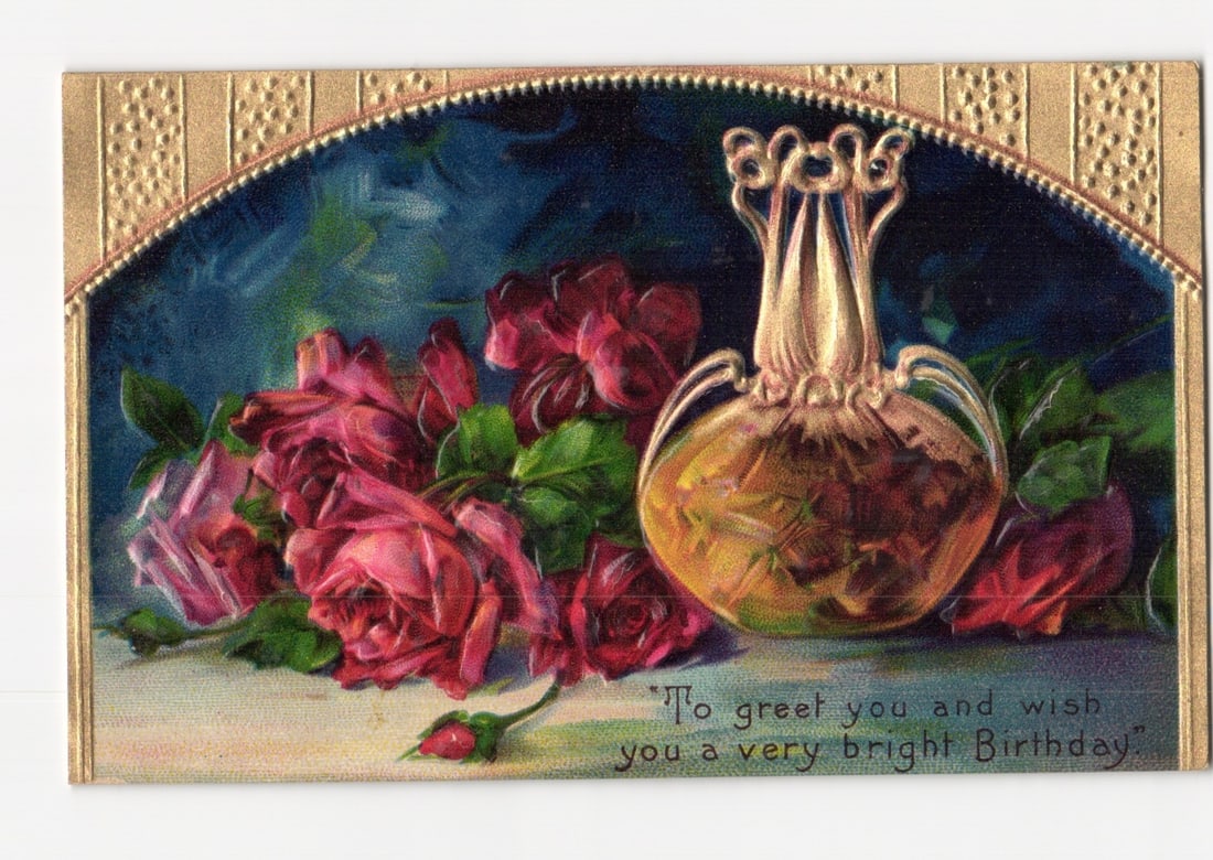 Embossed Birthday Greetings Postcard Featuring Red Roses and Ornate Perfume Bottle, Printed in: A central ornate, gold-toned perfume bottle with a stopper-like top is positioned to the right. To its left, a generous cluster of deep red roses and green leaves fills the lower-left quadrant of the 