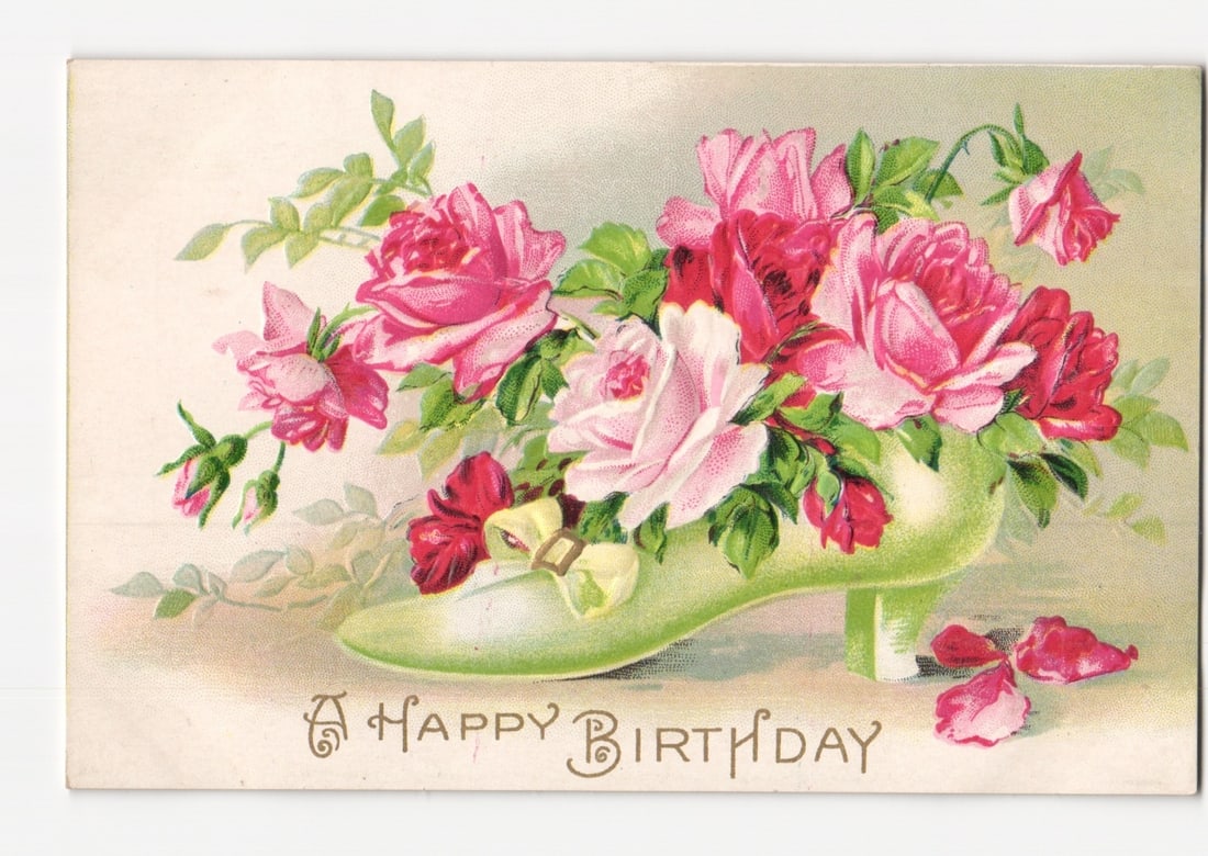 Chromolithograph Postcard: Pink and Red Roses Arranged in a Decorative Green High-Heeled Shoe, 'A: A light green high-heeled shoe is filled with a profusion of pink and red roses and green foliage. Additional rose petals are scattered near the shoe. The floral arrangement is centered against a ligh