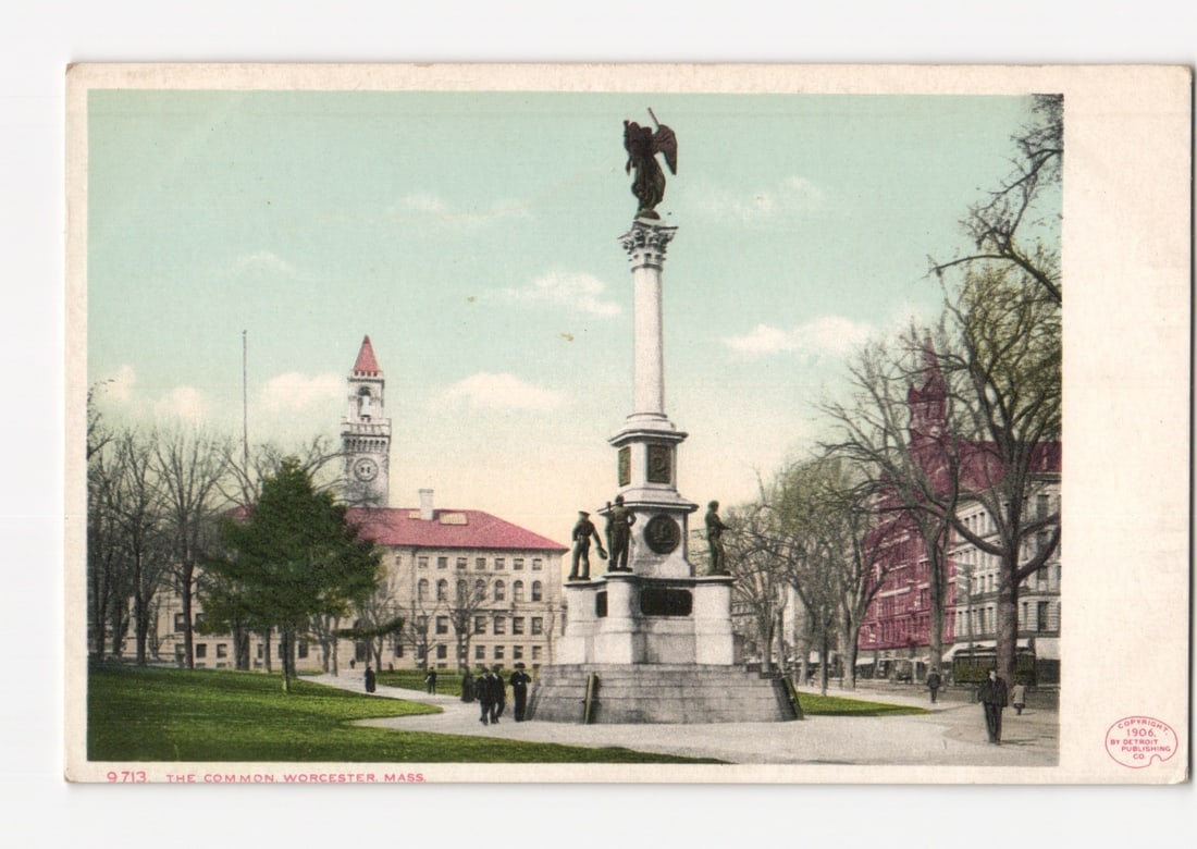 Worcester, Massachusetts: The Common Park & Monument Early 20th Century Postcard.: A central monument in a grassy park features a tall column topped by a winged figure, with four standing figures at its base. Bare trees frame the park on either side. In the background to the left st