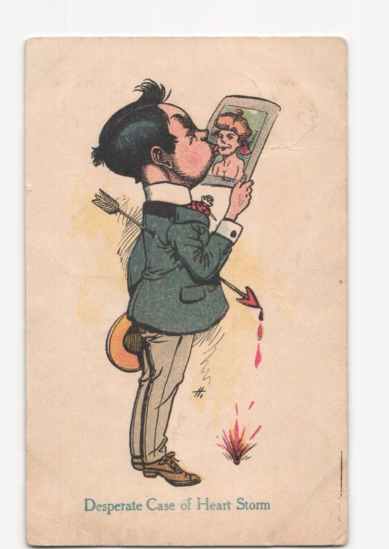 Cartoon postcard: Man kissing woman's portrait with Cupid's arrow and text 'Desperate Case of Heart: The image is a color illustration, likely a chromolithograph, depicting a man with dark hair, wearing a suit jacket and light trousers. He is shown in profile, leaning forward to kiss a small framed p