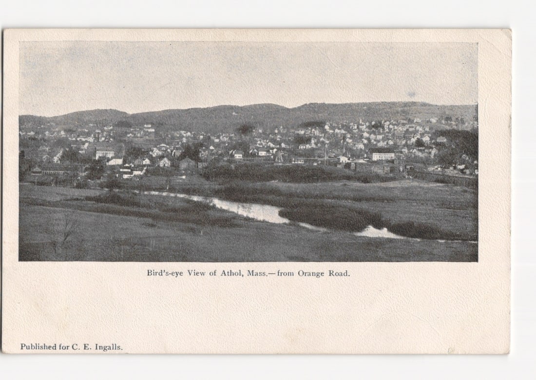 Bird's-eye View of Athol, Massachusetts, from Orange Road vintage photographic postcard: A monotone photographic print depicts a panoramic bird's-eye view of Athol, Massachusetts. The foreground features a winding river or stream traversing open fields, with scattered trees and vegetation
