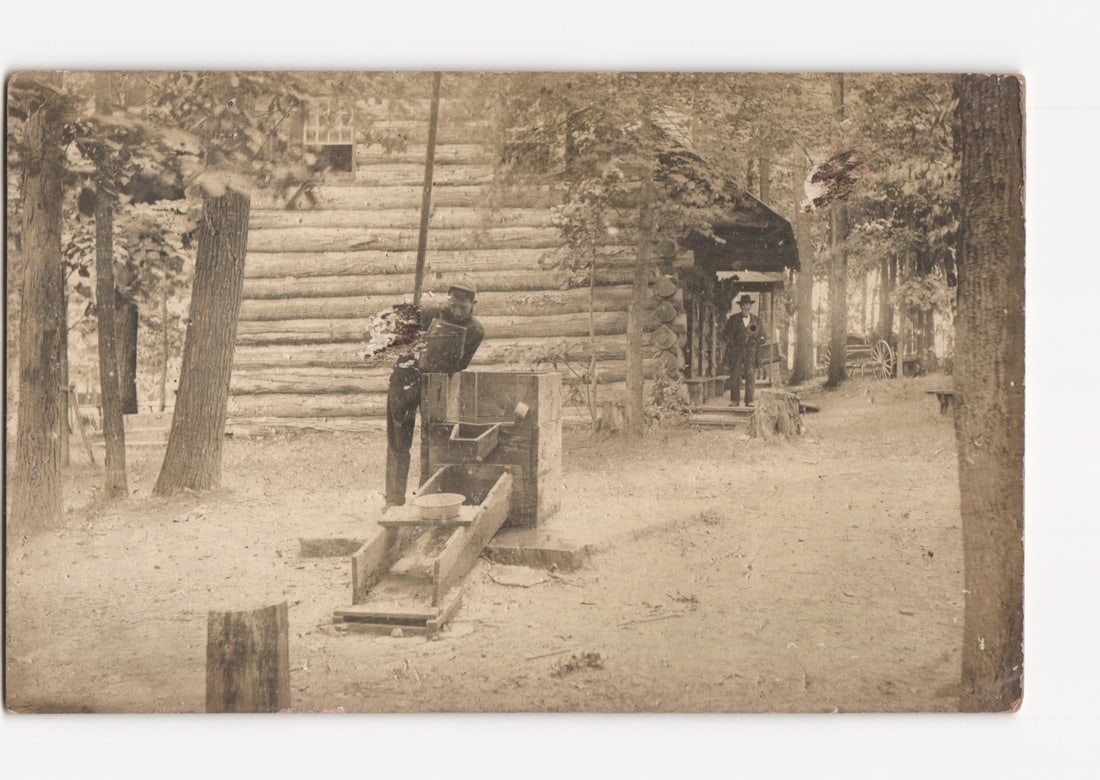 Early 20th Century postcard of two men with a sluice box at a rustic log cabin in a wooded setting (1 of 2)