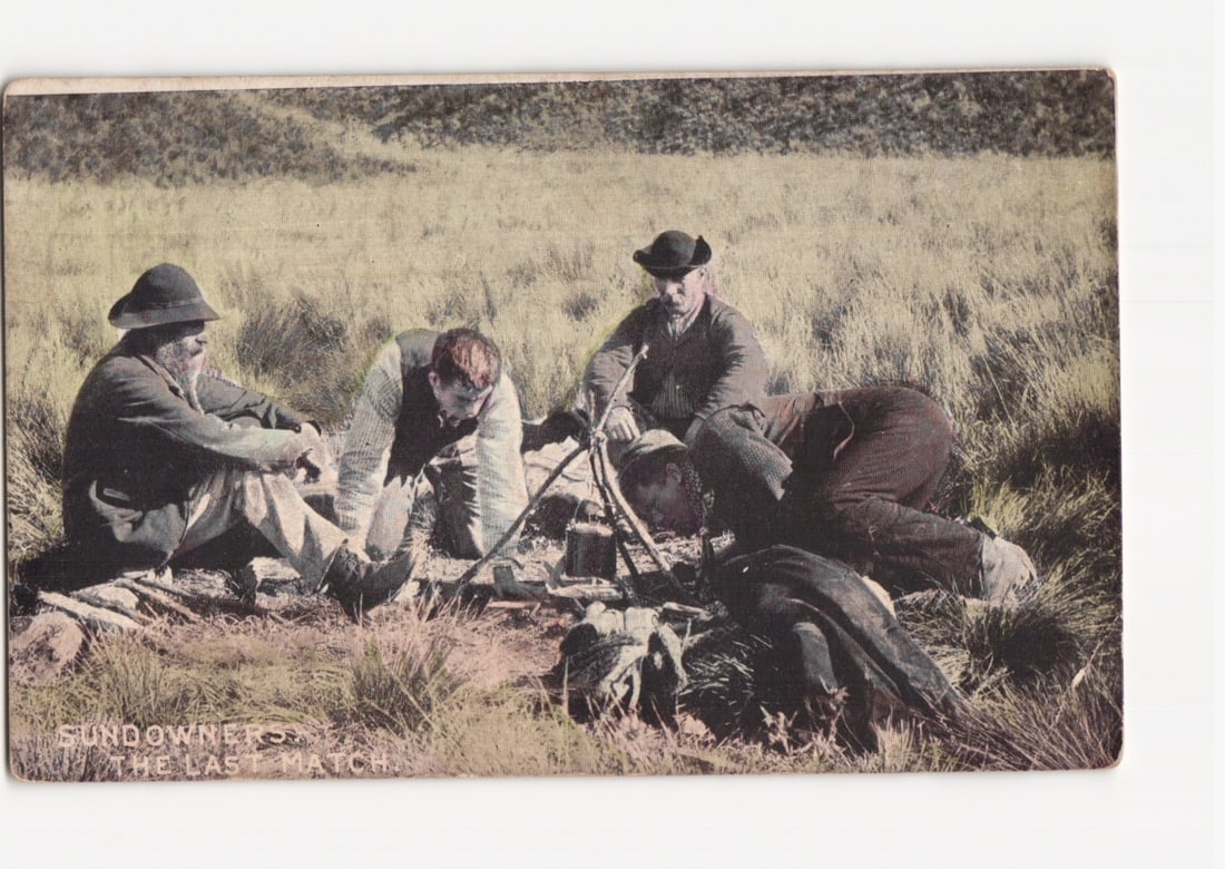 Early 20th Century Australian 'Sundowners' in Field, 'The Last Match' Scene Postcard: Four men are depicted in an outdoor setting, presumably a dry, grassy field. One man sits on the left, another kneels, a third crouches near a small fire with a tripod, and the fourth lies prone with 