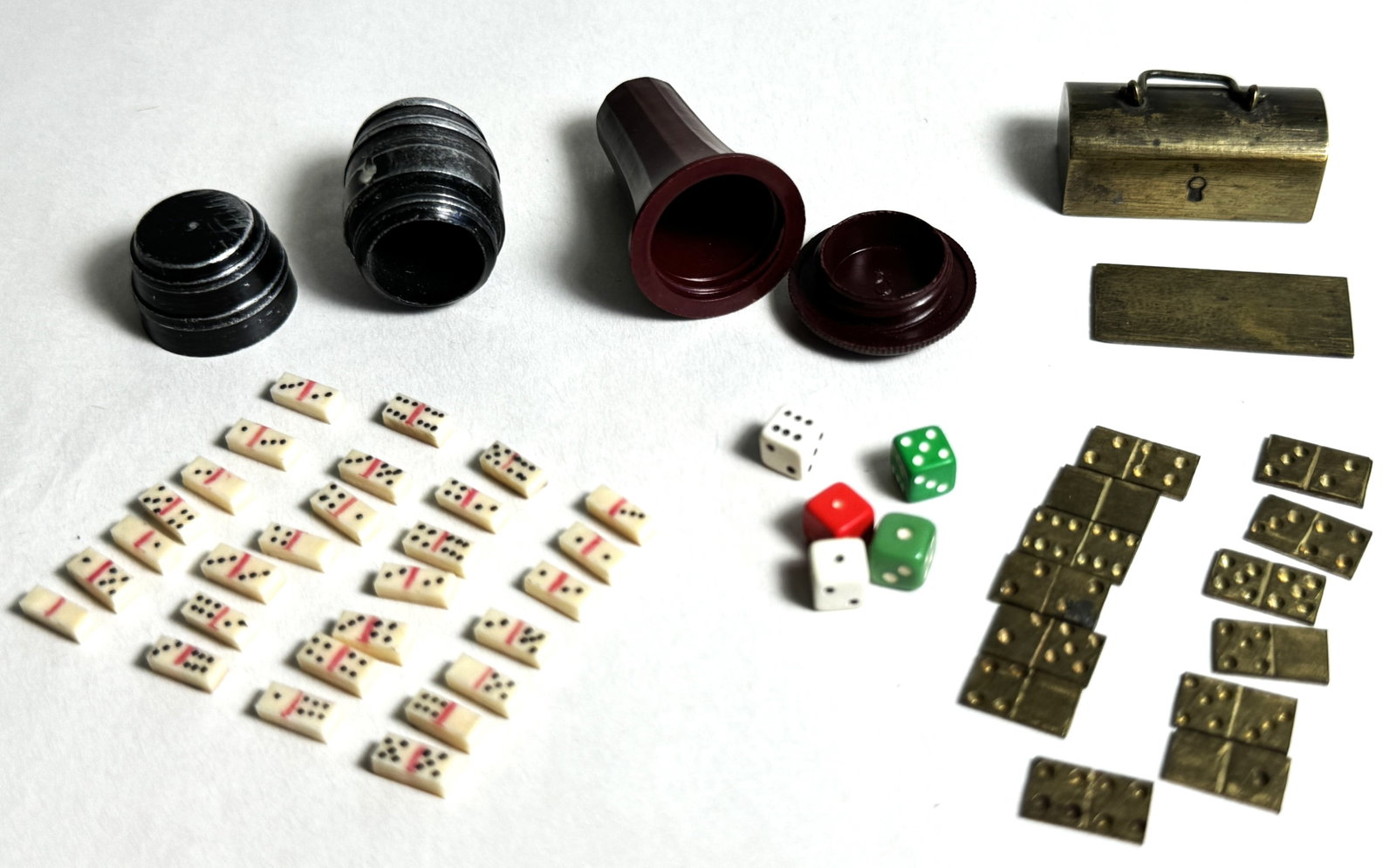 Miniature 20th Century Doll House Miniature Pocket Dice & Dominoes Lot: This is a fascinating lot of miniatures including a barrel of bone dominoes, brass tool box of brass dominoes and Bakelite treen style dice pod with appearingly plastic contemporary dice.
