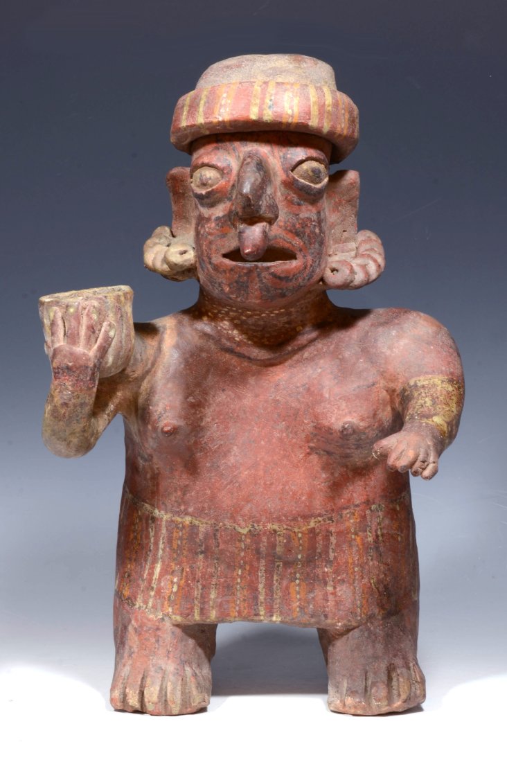 Pre Columbian Nayarit Ixlan Del Rio Pottery Standing Female: West Mexico, Protoclassic, ca. 100 B.C. - A.D. 250. An interesting rendition of a red ware standing female with fancy applied molded and painted details. She has a large pointed nose ornament, multi-s