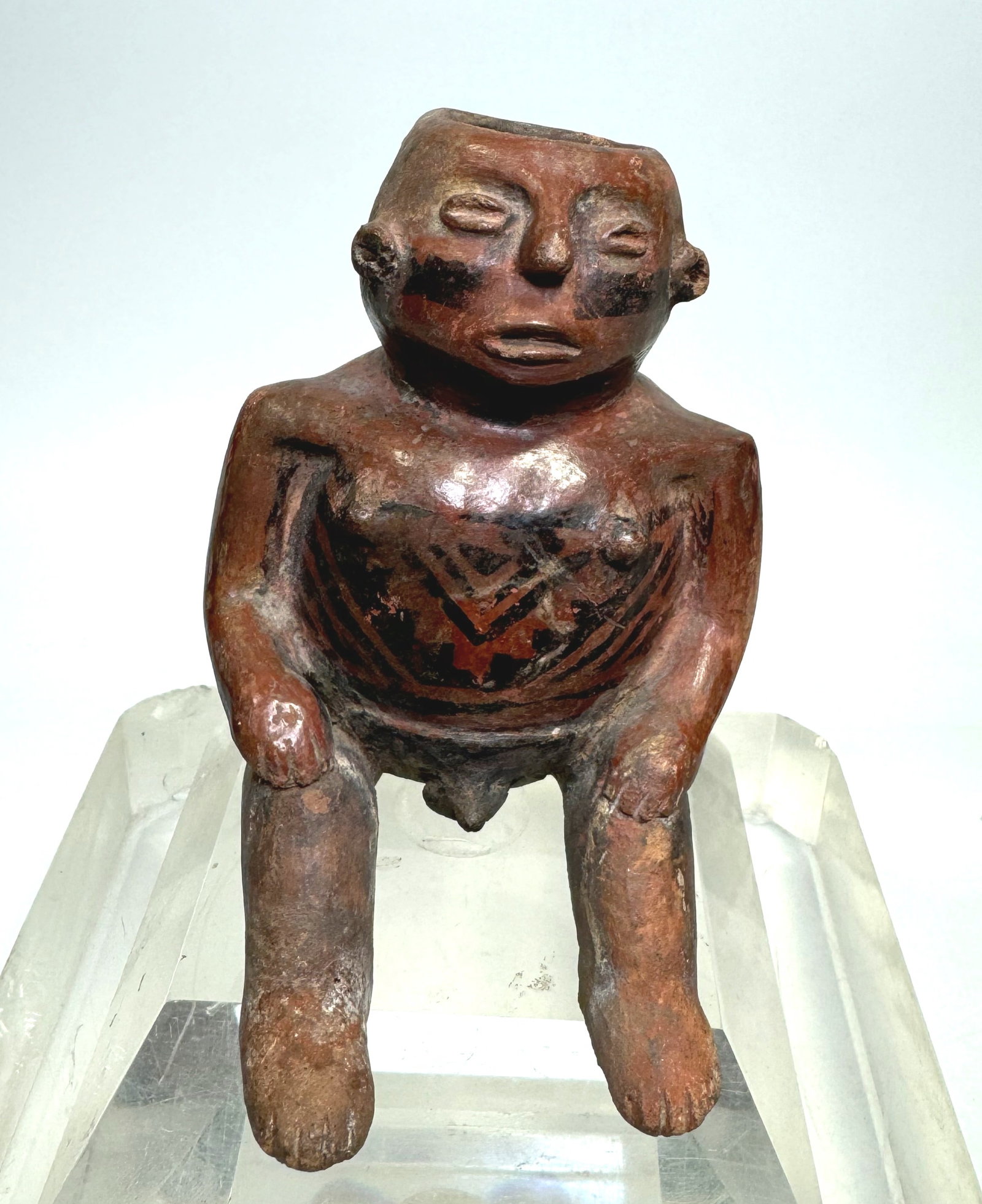 Good Narino Pottery Bichrome Seated Male Figure: from the Narino Complex, Highlands Colombia SA, Circa. 1100 to 1250 AD.Molded seated with legs in front and with wax resist design on face and as a textile shirt on body. Penis exposed. size approx 4.