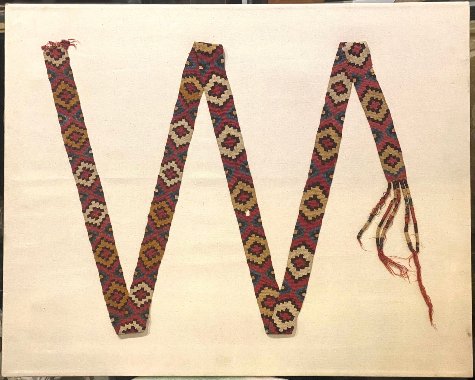Nazca Eye Dazzler Belt Band: Nazca Eye Dazzler Belt Band. South Coast Ca. 400 to 600 AD, A vibrant colorful slit weave woven with alternating checker board. approx 84 in L. x 1-3/4 in W.; mounted as a zig zag; 30 in x 24 in. Prov