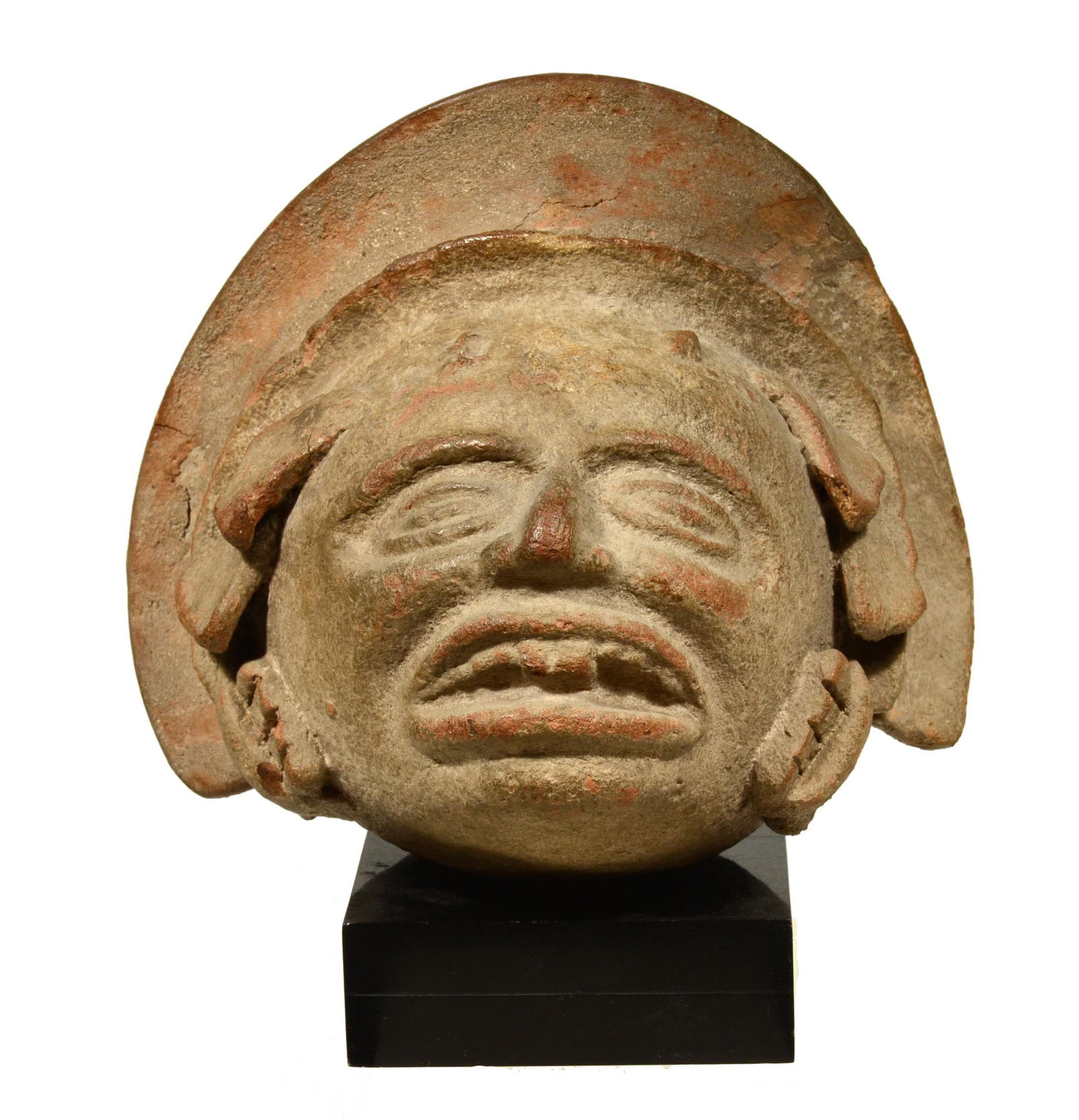 Pre-Columbian Huastec Pottery Trophy Head: Panuco River, Mexico, Panuco III Circa 300 to 600 A.D. . Expressive head with a wide brim headdress, ornaments attached tightly to ears and mouth which is slightly parted with delineated teeth. Size 6