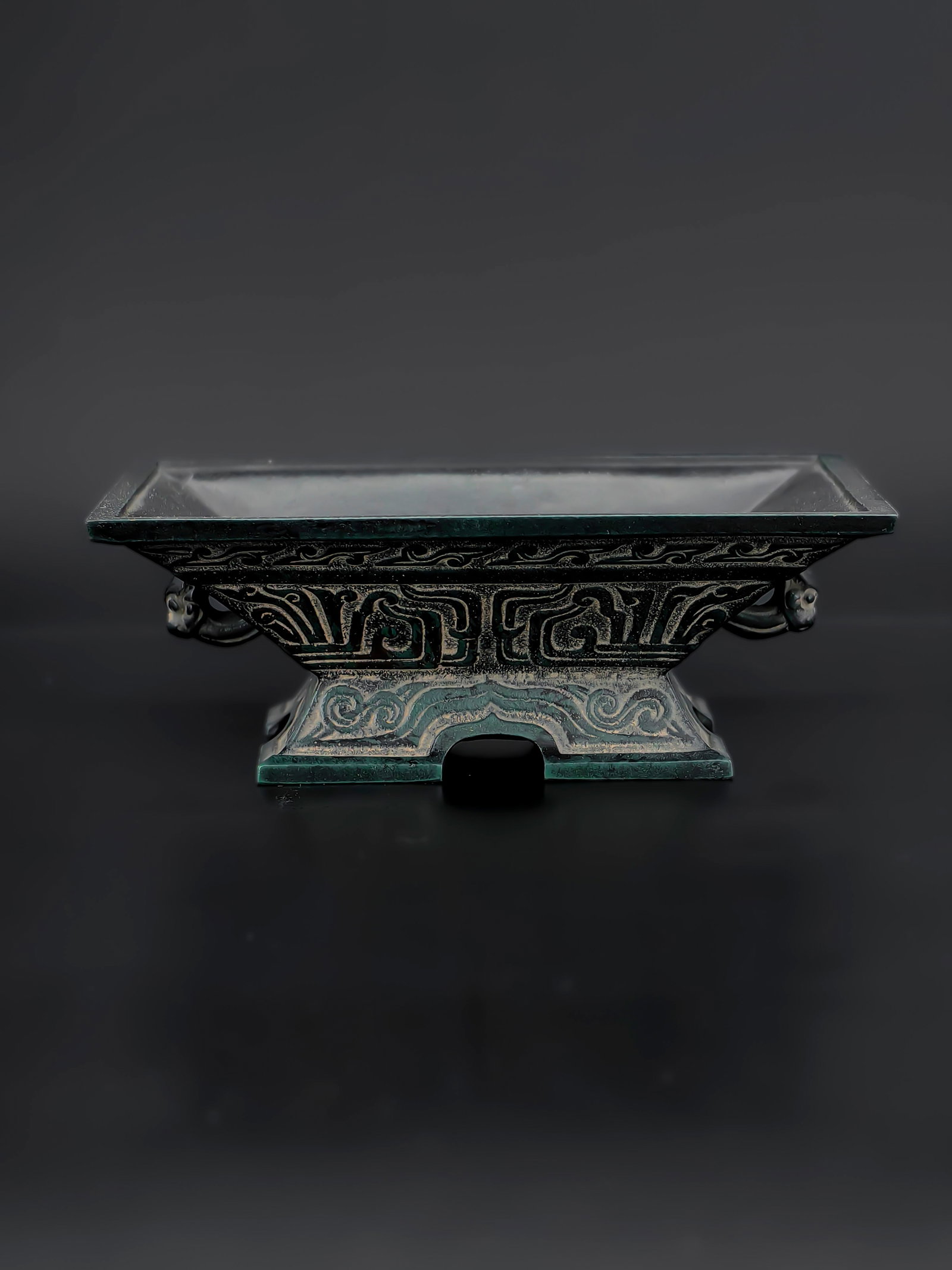An Antique Bronze Censer: A finely cast Chinese 18th' bronze censer in archaistic style, of rectangular form with flared sides and a stepped foot. The exterior is richly decorated with stylized taotie and scrolling cloud