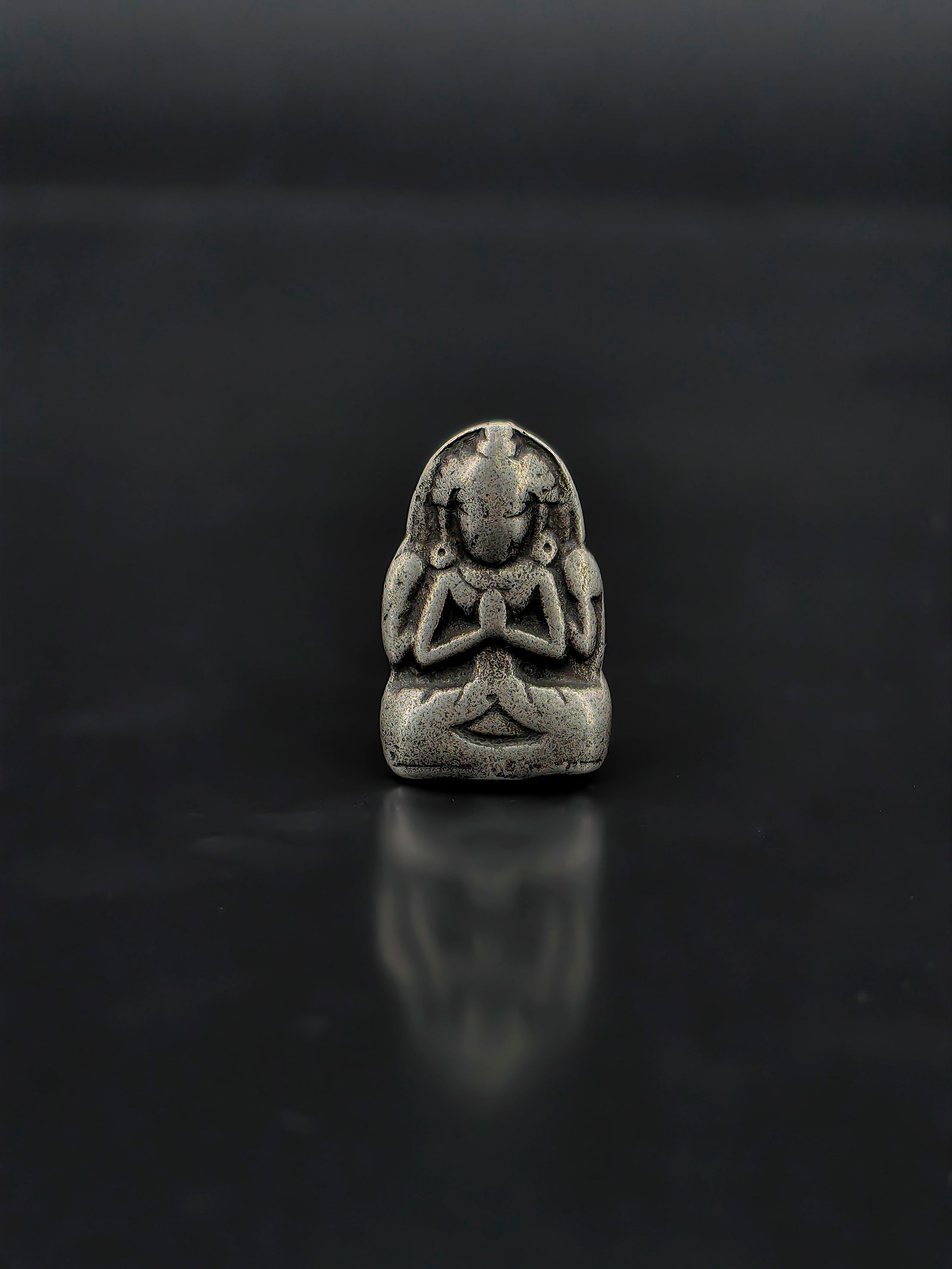 An Antique Chinese Metal Buddha Pendant: Antique Chinese small metal Buddha pendant or amulet, likely dating to the Qing Dynasty. The figure is cast seated in a meditative posture with hands joined in prayer, displaying a serene expression