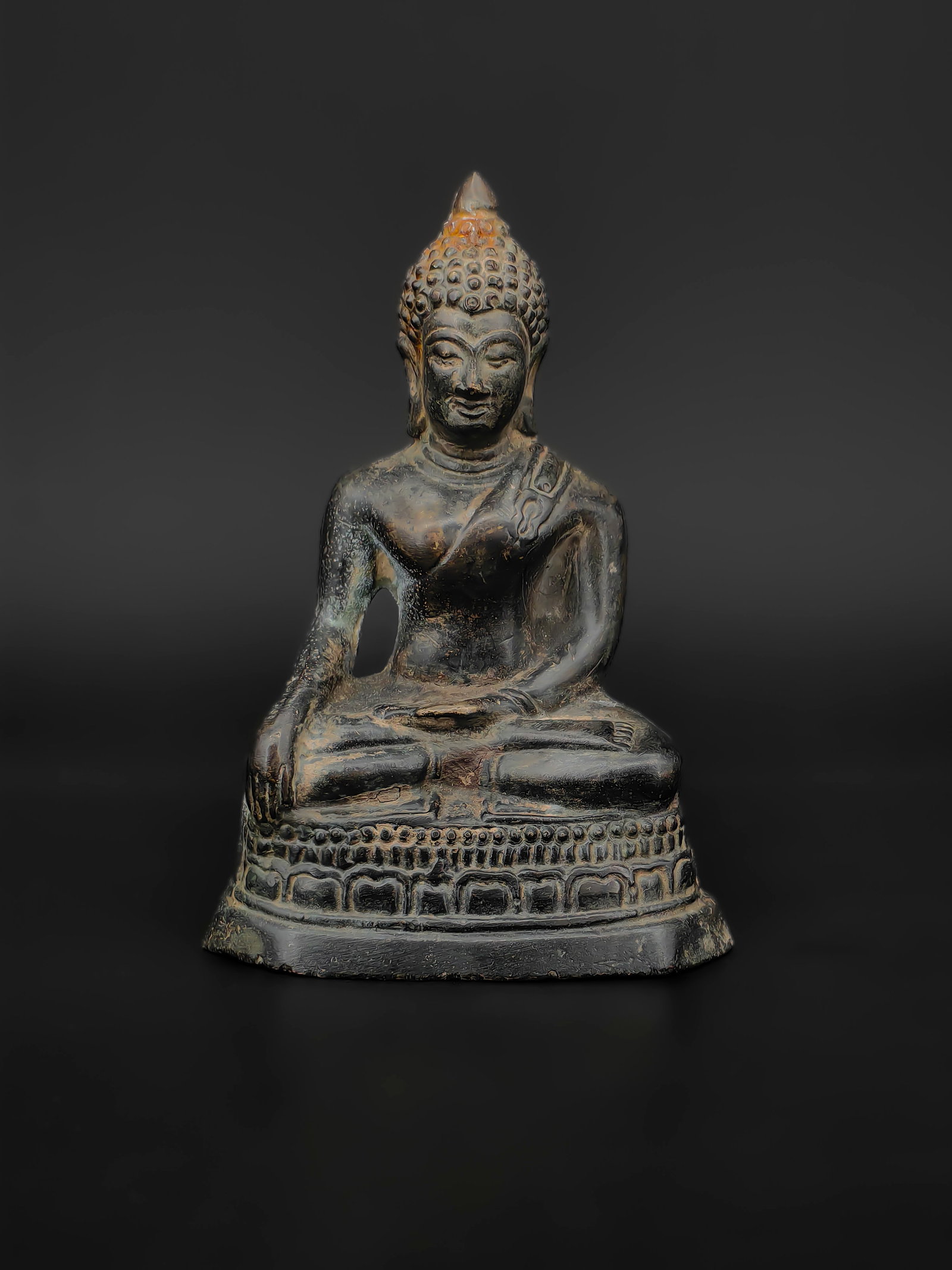 An Ancient Asian Bronze Seated Buddha: This Southeast Asian Bronze Seated Buddha depicts the Buddha in the padmasana (lotus position) on a lotus pedestal, with the right hand in the Bhumisparsha mudra (earth-touching gesture). The figure