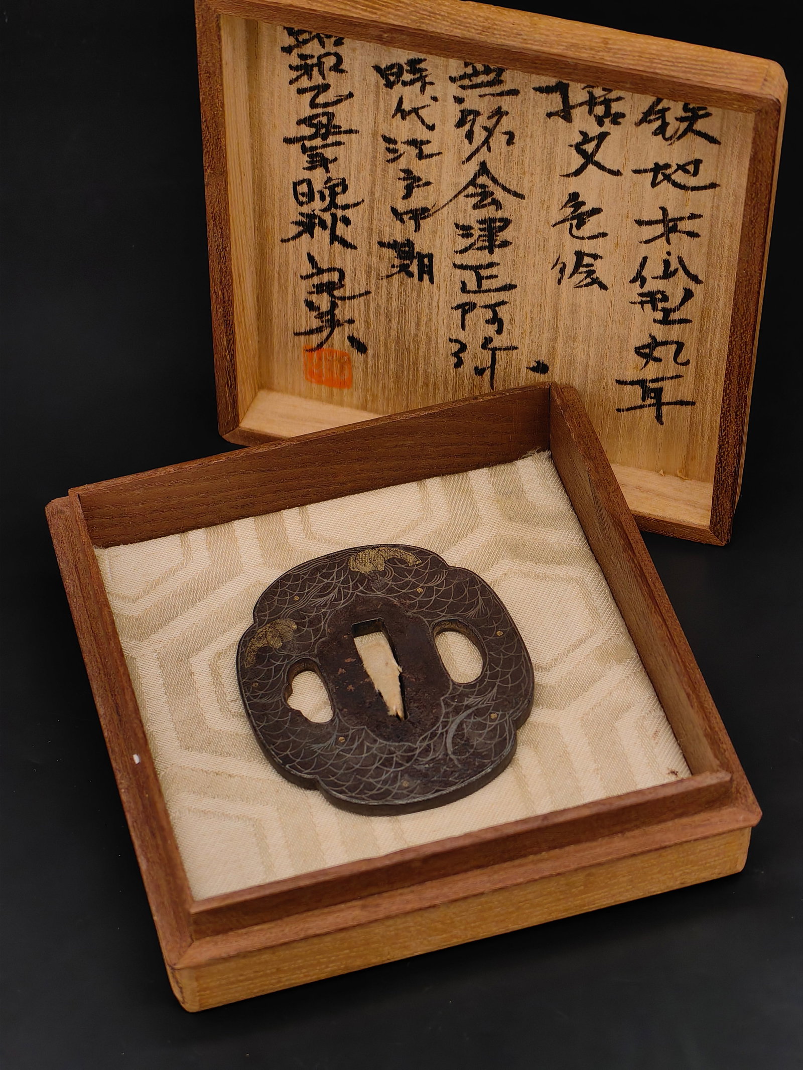 A Japanese Edo Period Iron Tsuba: This exceptional piece features a dense wave pattern (Nami) meticulously engraved across the surface. The composition is elevated by fine gold and silver Zogan (inlay) representing foam or celestial