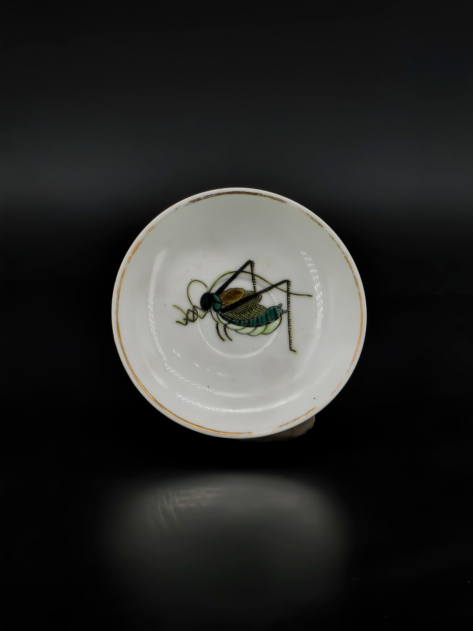 A Chinese Qing Dynasty Famille Rose Saucer: This exquisite saucer, approximately 10cm in diameter, features a finely potted white porcelain body. The interior is vibrantly decorated in famille rose enamels with a lifelike cricket, showcasing