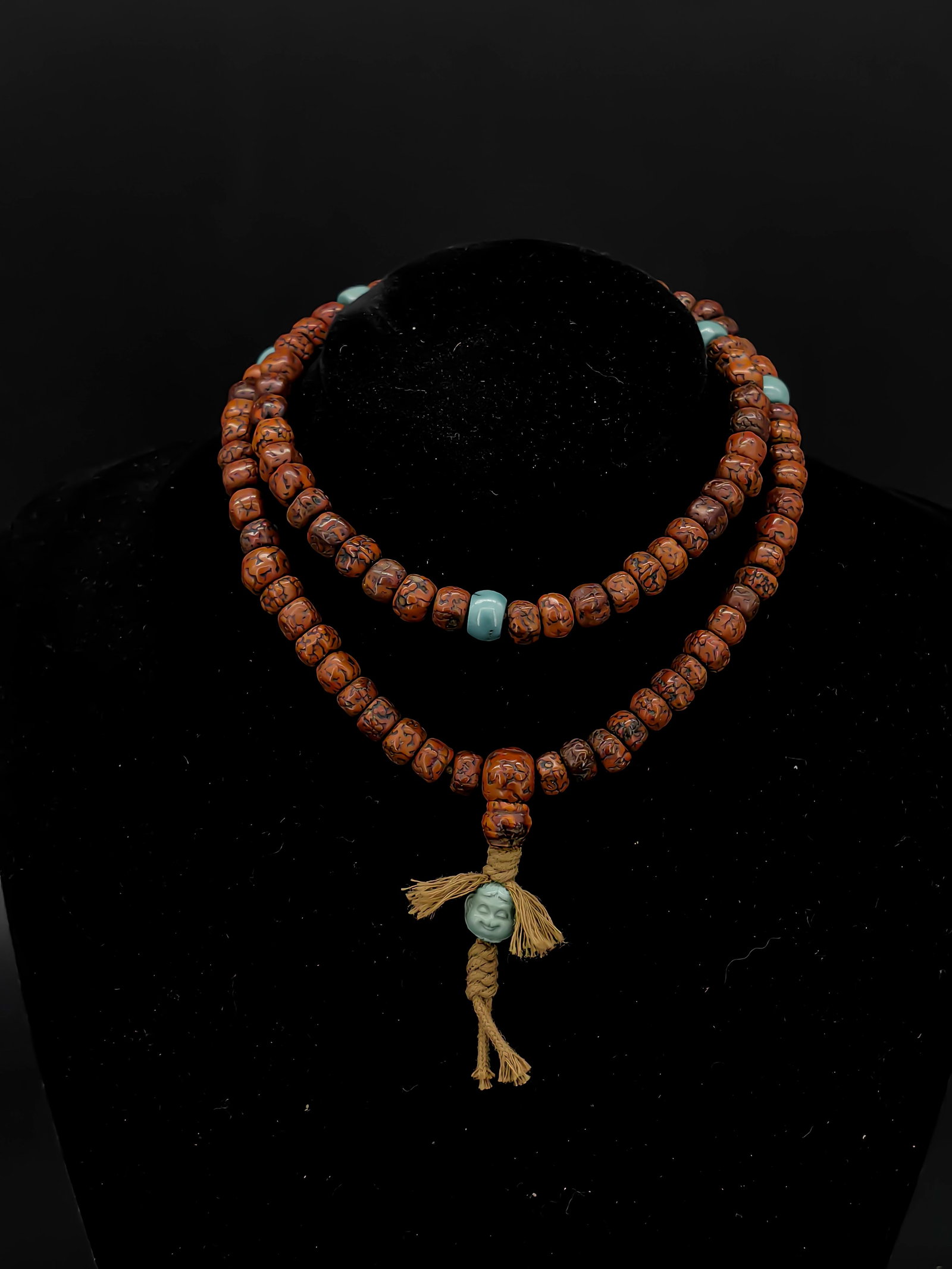 An Antique Rudraksha Prayer Beads: This is an exquisite set of aged Rudraksha prayer beads. The beads possess a rich, reddish hue and a translucent, agate-like patina developed from years of handling. It is accented with several turquo