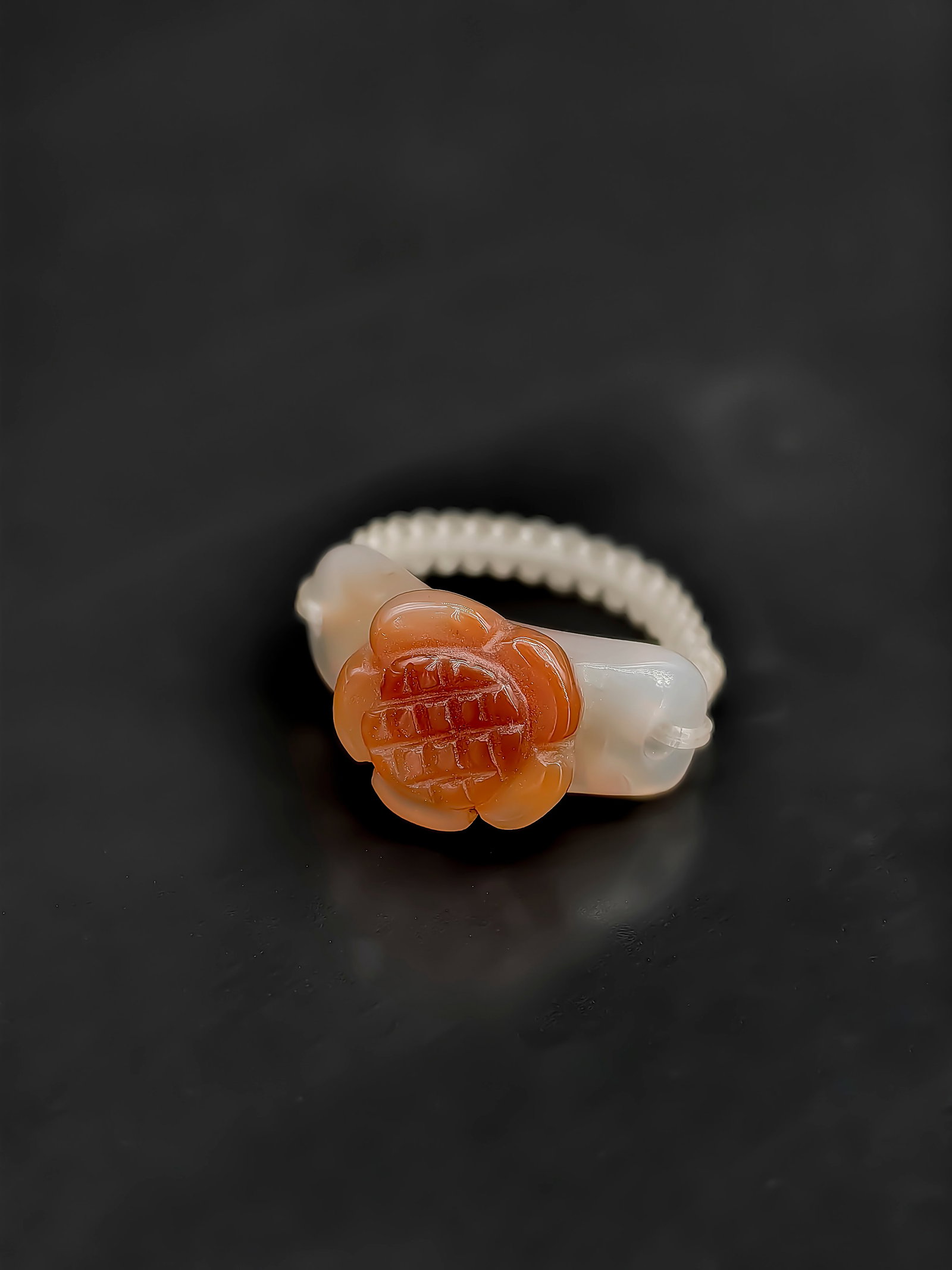 An Antique Agate Ring,Republic Period: This exquisite 19th-century agate ring showcases a masterful use of natural coloration. The face of the ring is carved from the vibrant red section of the agate, featuring a plump five-petaled flower