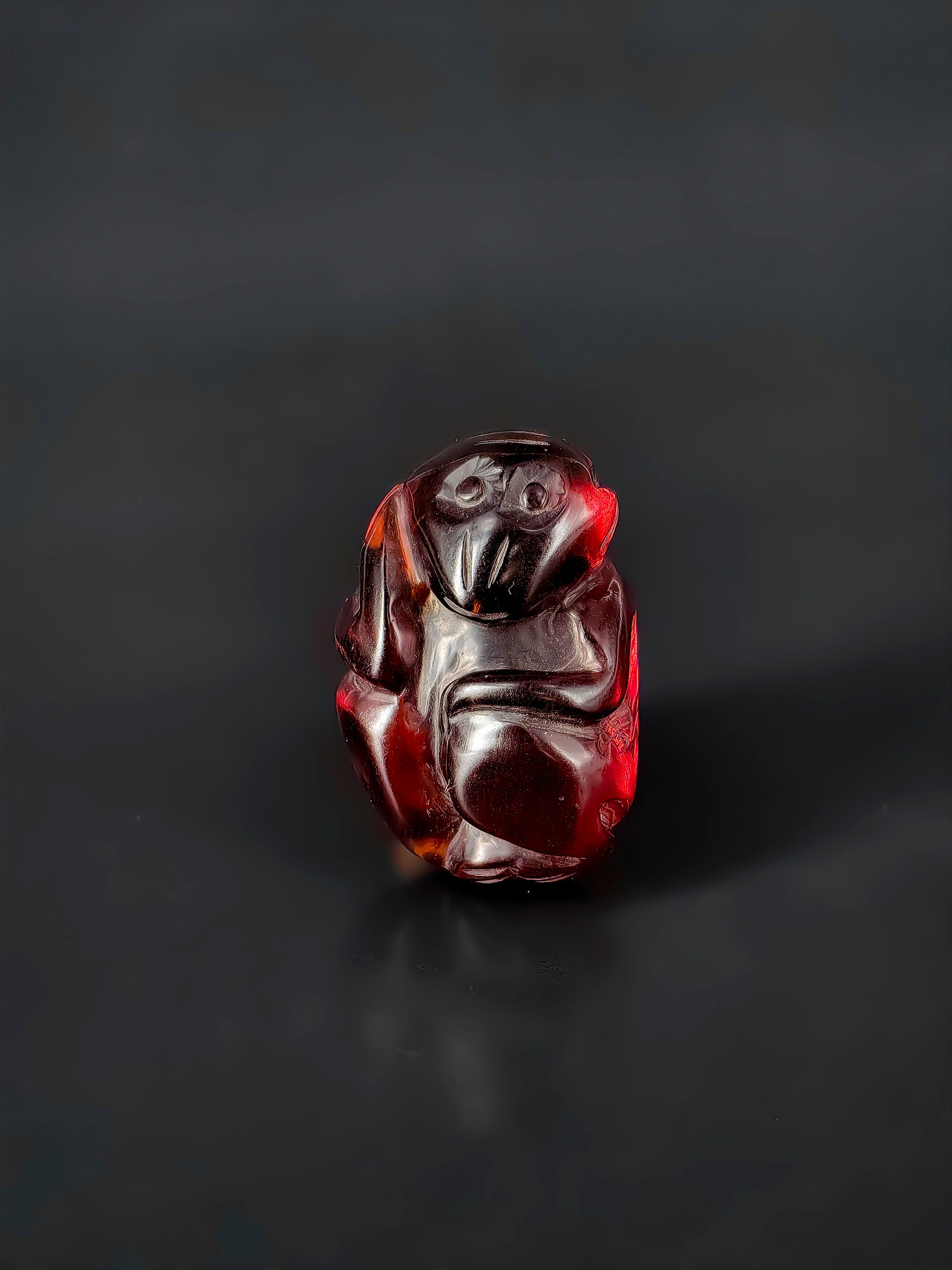 An Antique Chinese Amber Monkey,Republic Period: This is an exquisite, small blood amber carving of a monkey, measuring approximately 3.5cm. The craftsmanship features a primitive yet refined style with smooth lines. The monkey is depicted in a