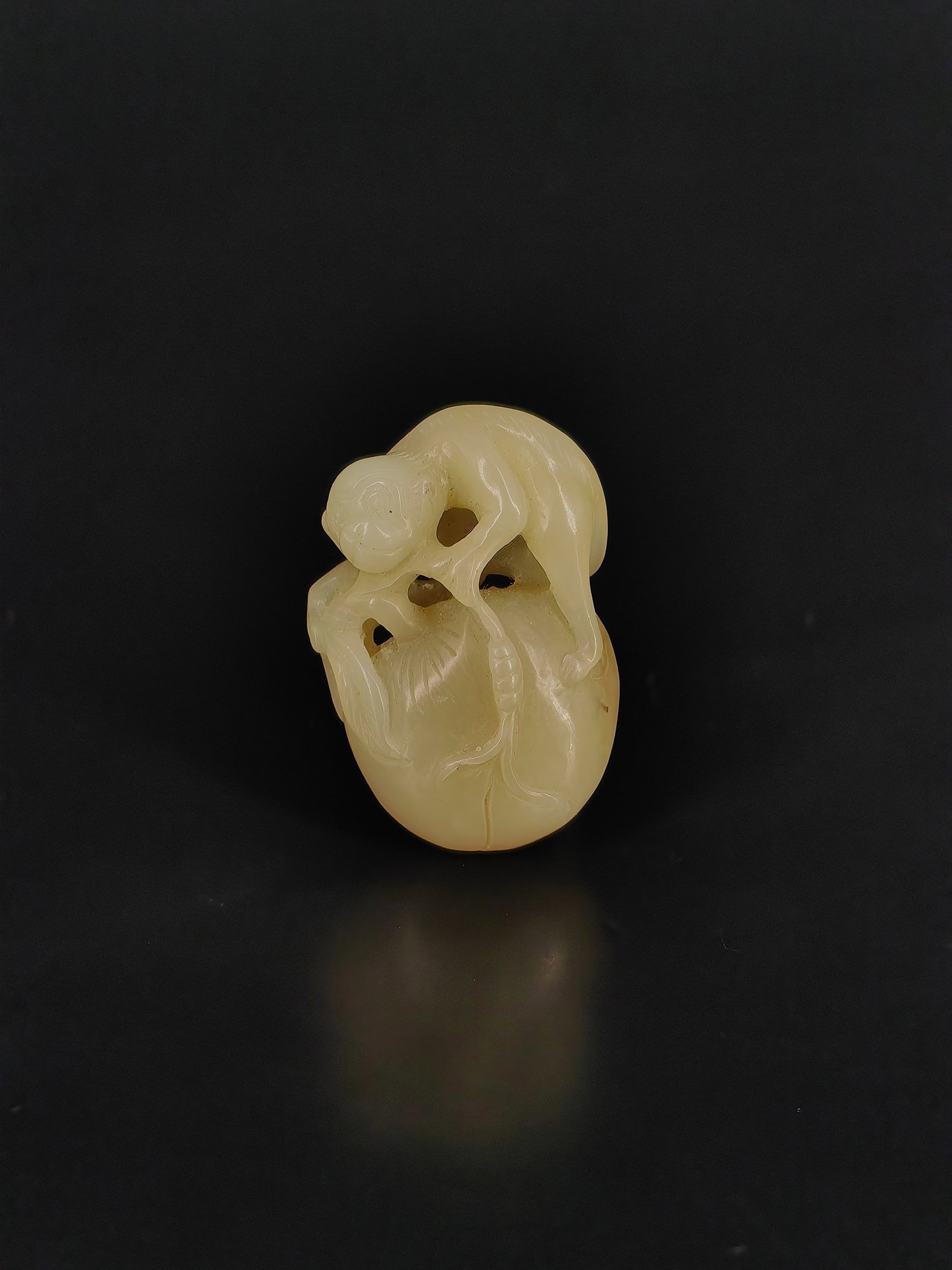 An Ancient Jade Pendant: This is an exquisite round-carved jade pendant depicting a clever monkey offering a longevity peach. Crafted from white jade with a warm texture and natural skin tones, it features a lively monkey